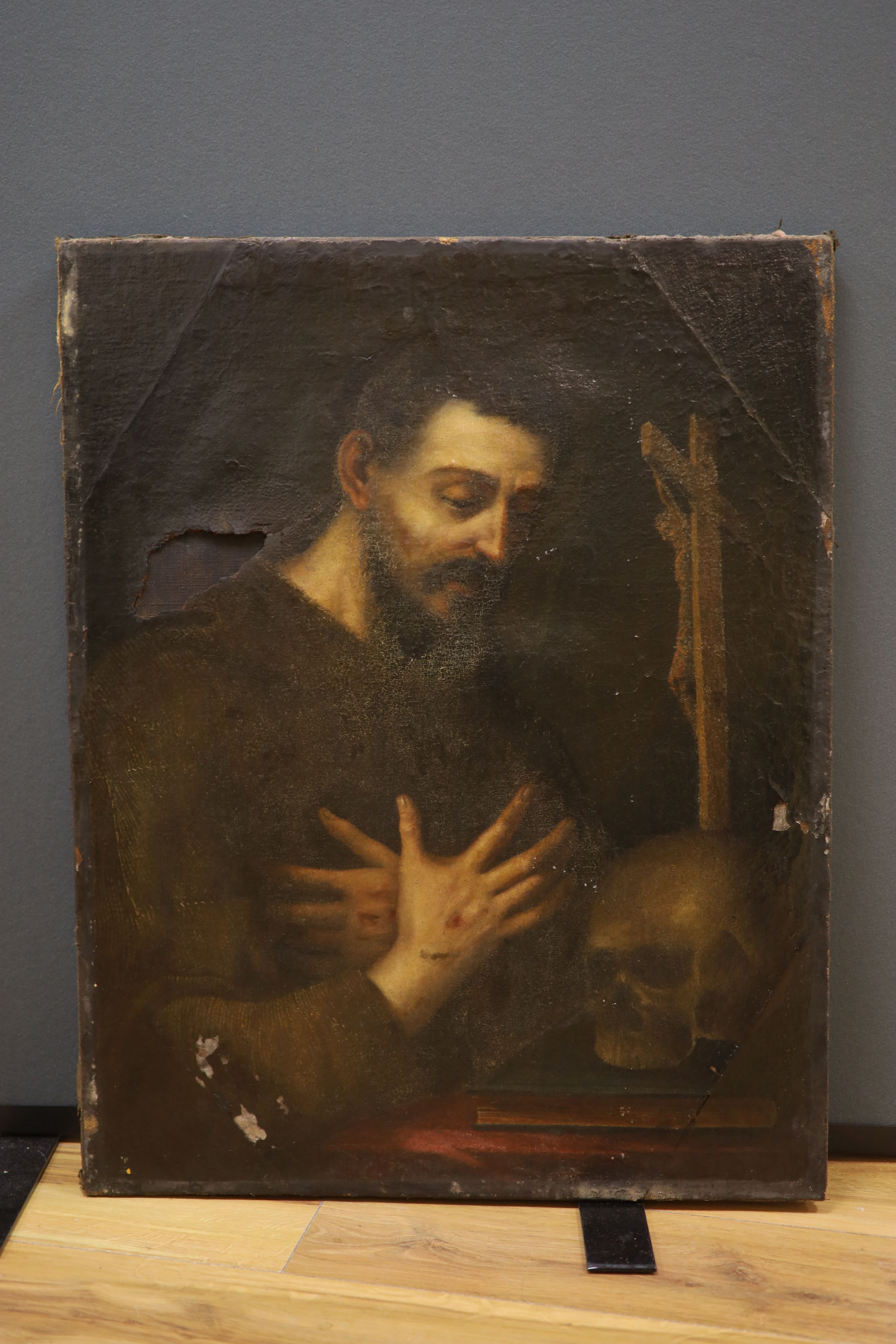 19th Century Continental School, oil on canvas, study of a monk in contemplation, the figure beside a desk with a skull, bible and crucifix, his hands bearing stigmata, (A/F) 74 x 58 cm.